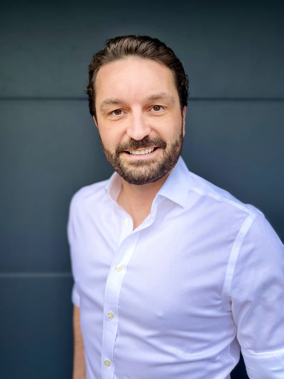 Edward Worthington, founder of whoot., in a white open-collared shirt against a dark grey wall